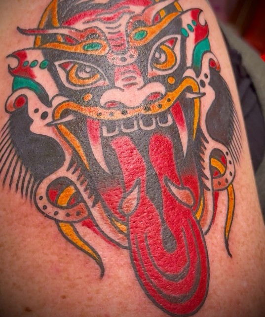 Foo dog face tattoo with red tongue